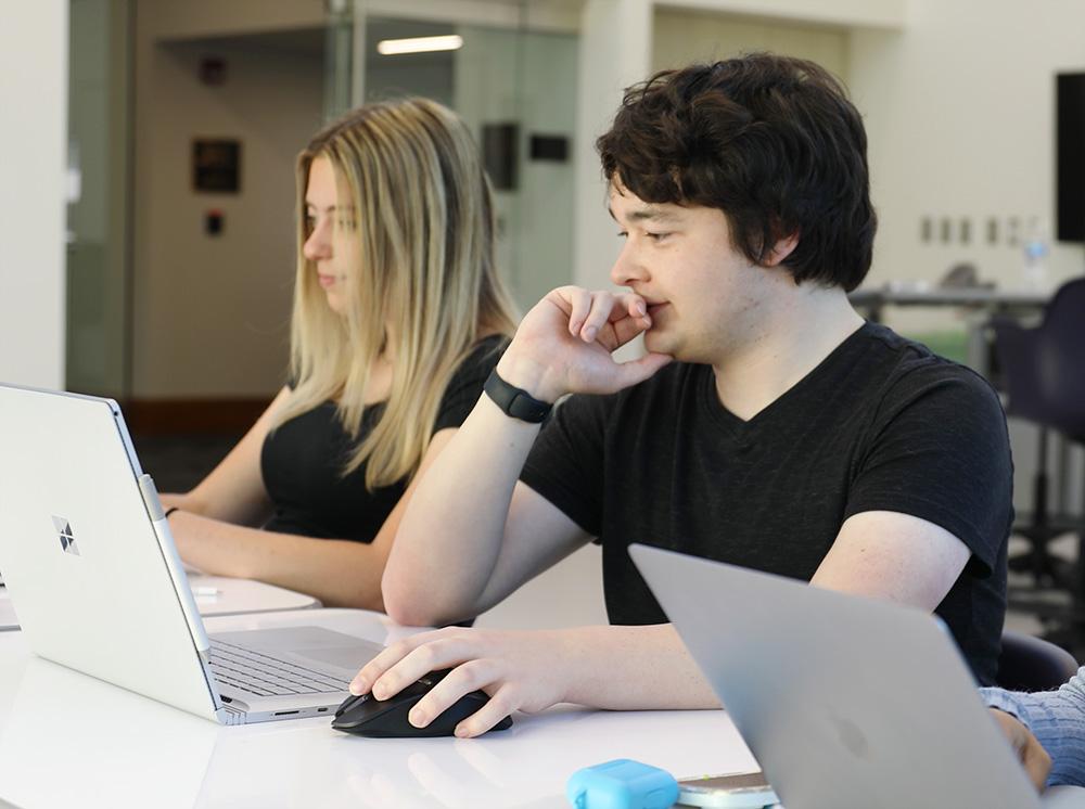 two students working on laptops